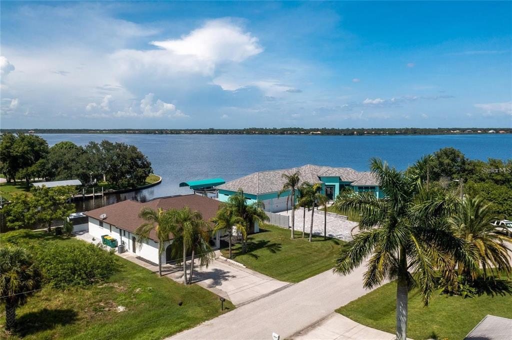 An aerial view shows two waterfront houses with palm trees and a boat dock — 12420 MINOT AVENUE, PORT CHARLOTTE, FL