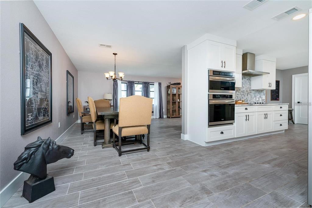 A dining area with tan chairs and a kitchen featuring white cabinets and stainless appliances — 12420 MINOT AVENUE, PORT CHARLOTTE, FL