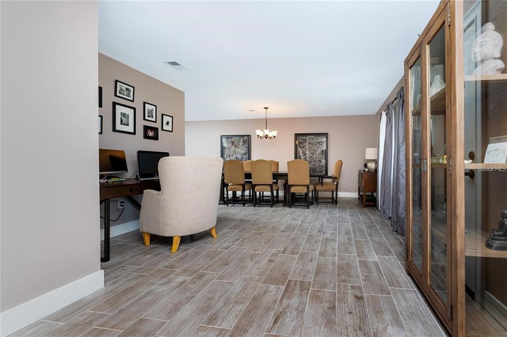 A dining room with wood-look tile floors, a desk area, and a wooden display cabinet — 12420 MINOT AVENUE, PORT CHARLOTTE, FL
