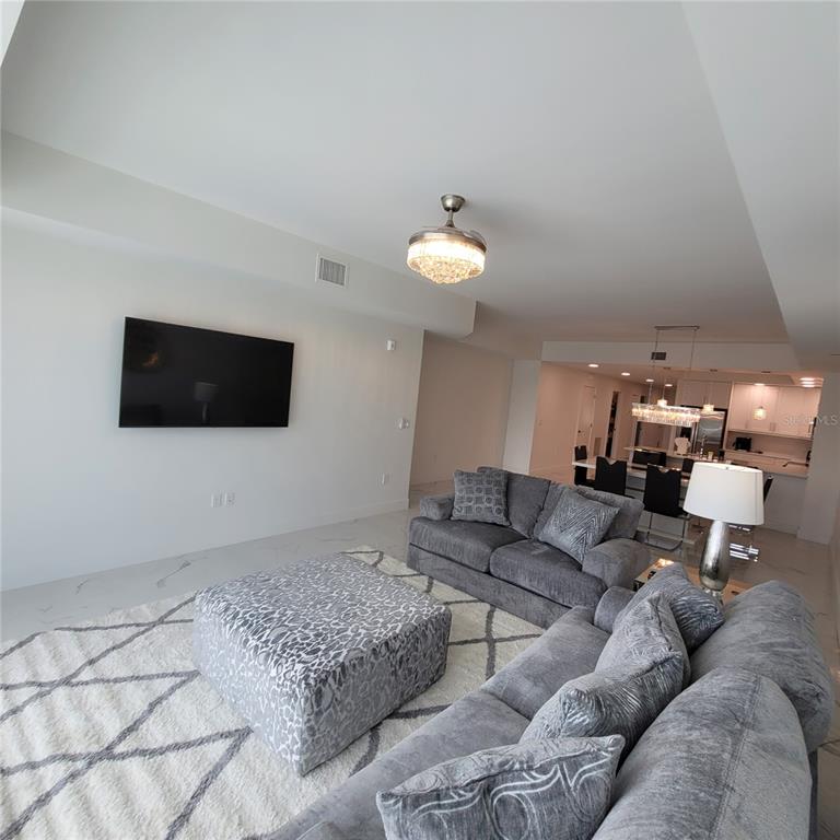 A living room with gray furniture, a patterned ottoman, and a white rug on tile floors — 415 ISLAND WAY UNIT 206, CLEARWATER BEACH, FL