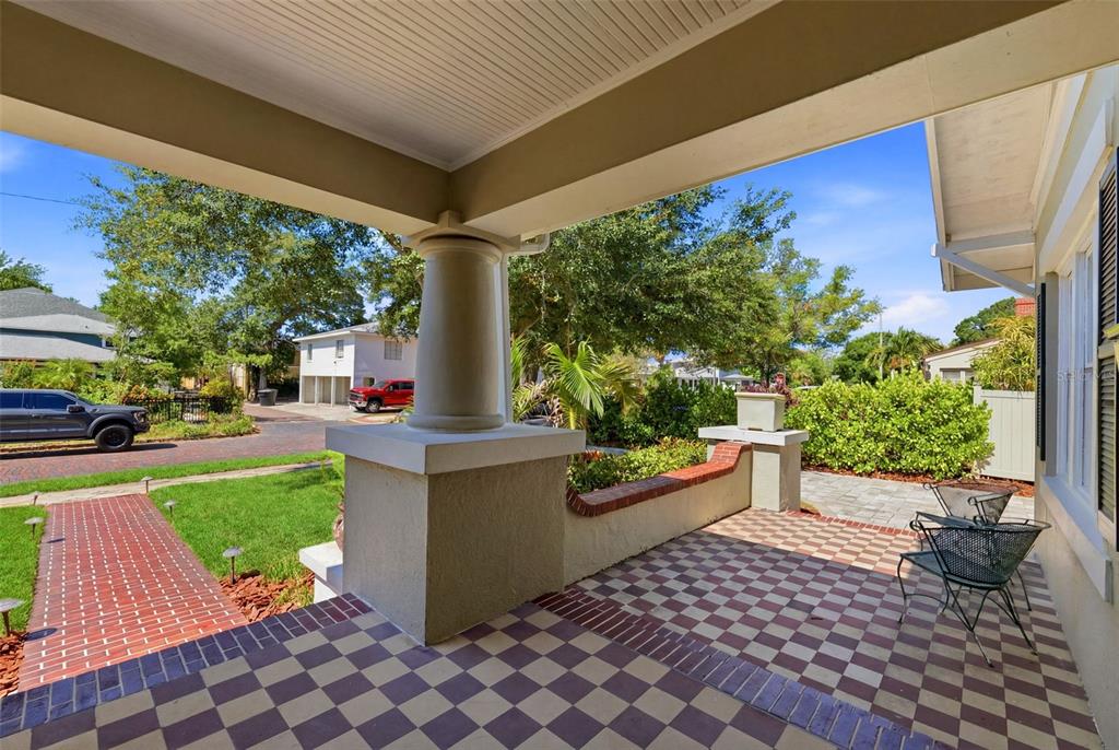 A covered front porch features a checkered tile floor, a large pillar, and brick accents — 871 17TH AVENUE N, ST PETERSBURG, FL