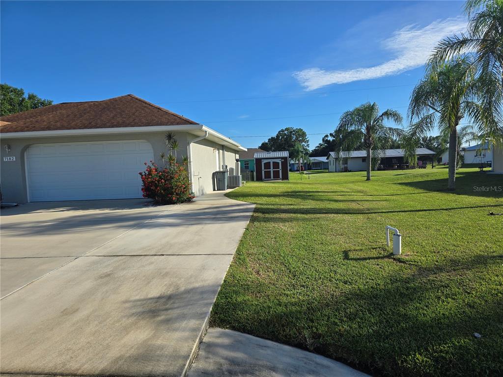 A concrete driveway leads to a garage next to a grassy yard with a shed — 7182 SW BIRD ROAD, ARCADIA, FL