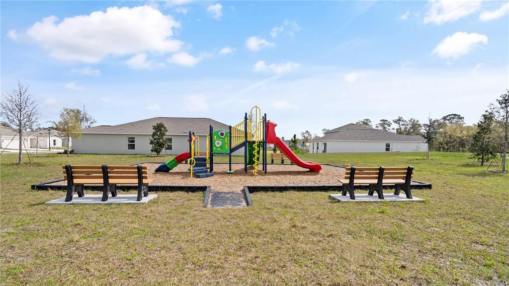 A playground with a slide and climbing structure sits between two benches on a lawn — 1367 BLUE ASH LANE, DELAND, FL