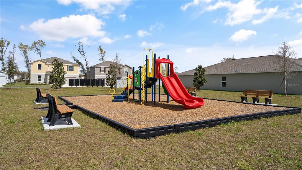 A playground with a red slide and benches sits on a wood-chipped lot outdoors — 1367 BLUE ASH LANE, DELAND, FL