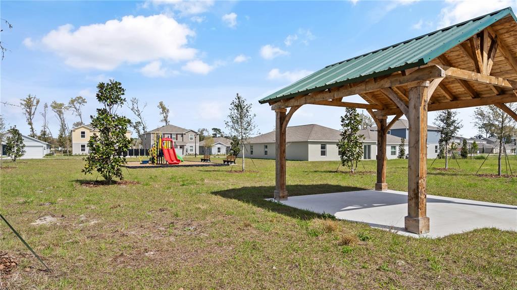 A wooden pavilion with a green metal roof stands in a grassy neighborhood park — 1367 BLUE ASH LANE, DELAND, FL