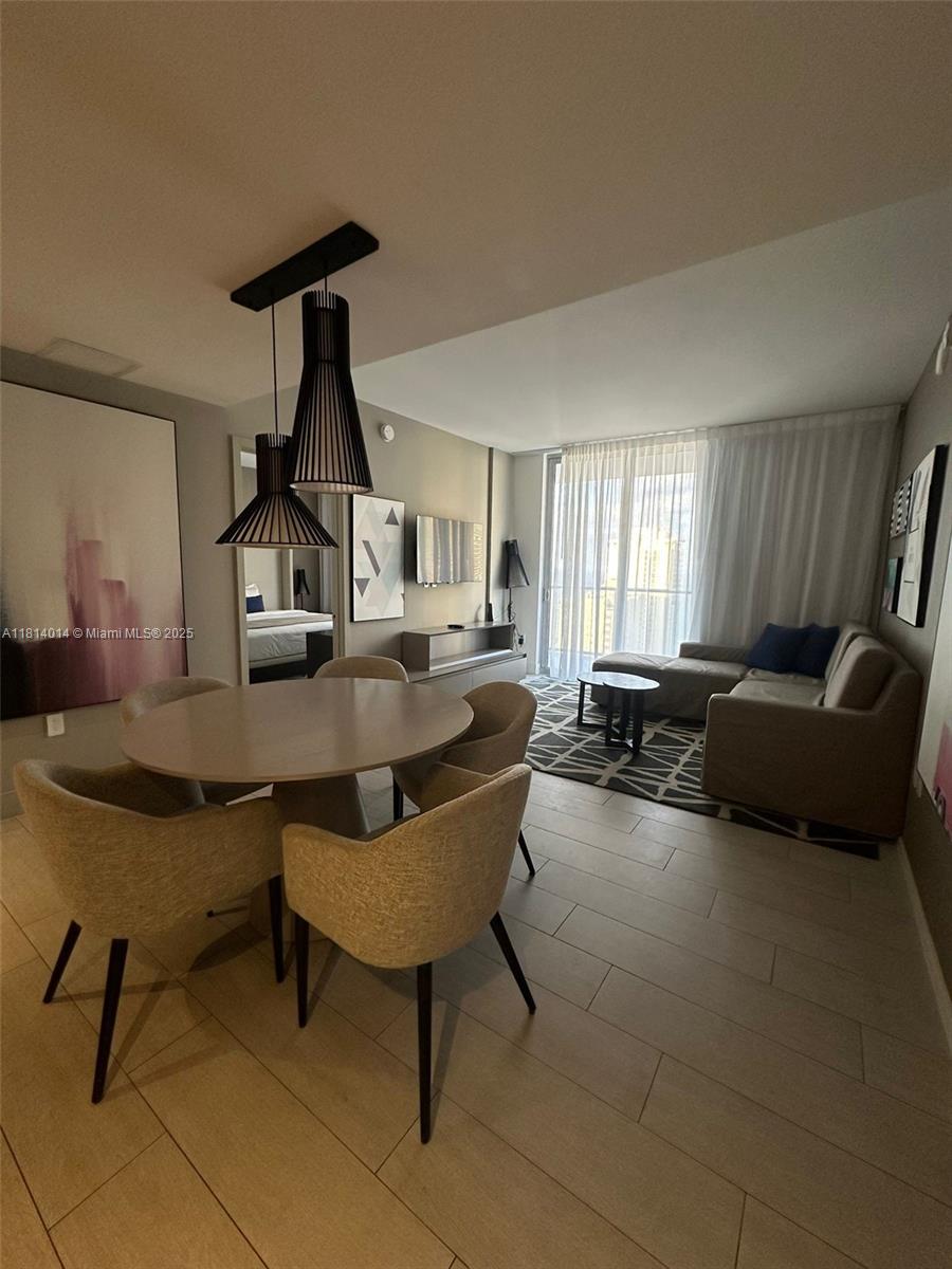 This open-concept living and dining area features light wood-look tile floors and modern pendant lighting — 4010 S Ocean Dr # R1707, Hollywood FL 33019, HOLLYWOOD, FL