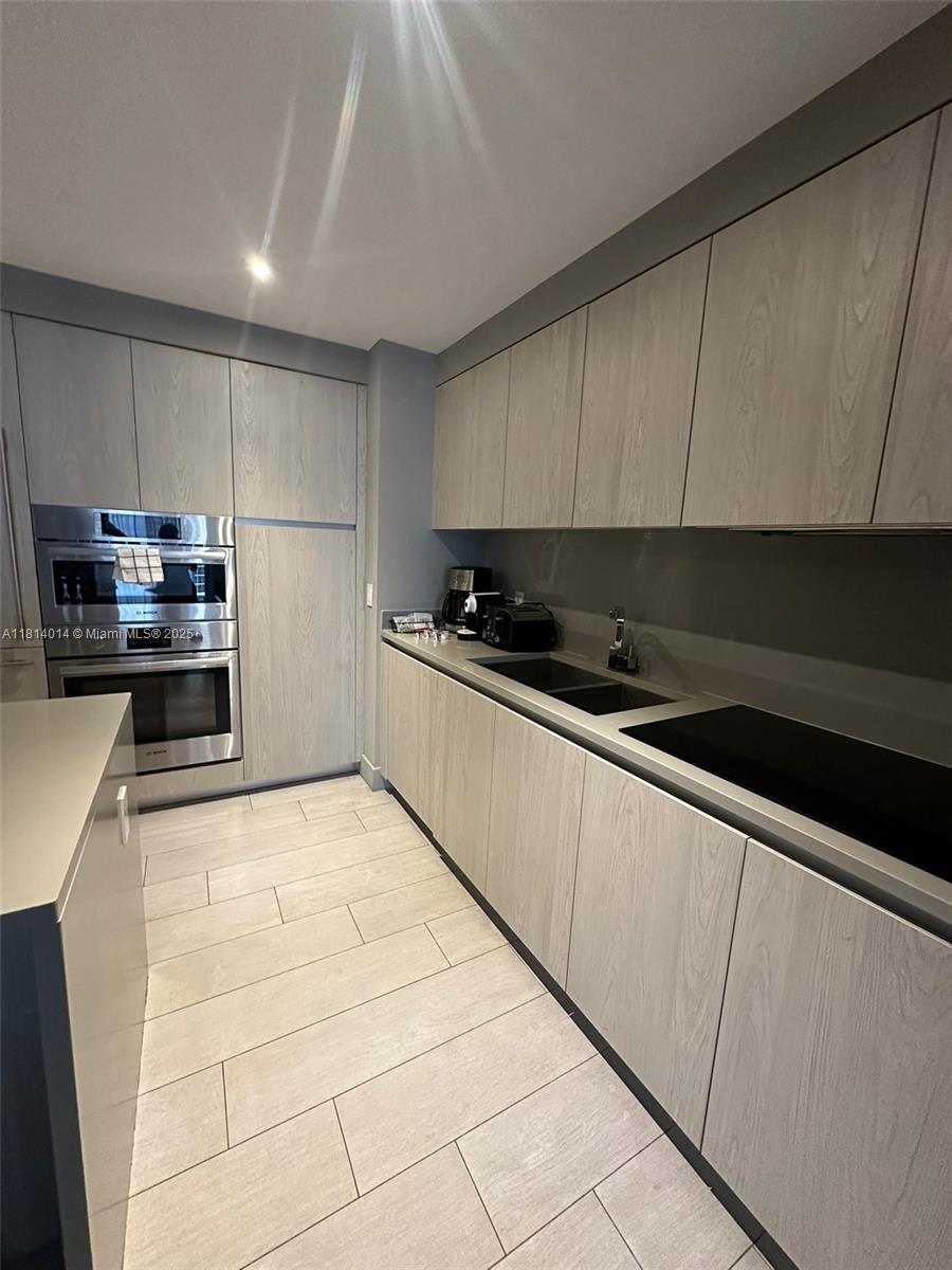 This modern kitchen features light wood-grain cabinetry, stainless steel appliances, and light-colored tile flooring — 4010 S Ocean Dr # R1707, Hollywood FL 33019, HOLLYWOOD, FL