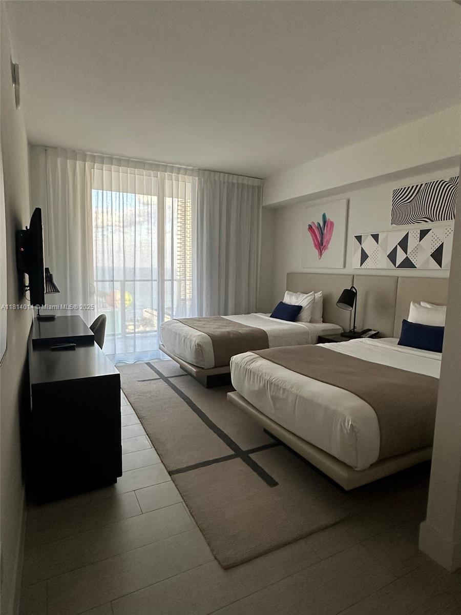 A bedroom features two beds, a desk, and a balcony with a view of the ocean — 4010 S Ocean Dr # R1707, Hollywood FL 33019, HOLLYWOOD, FL
