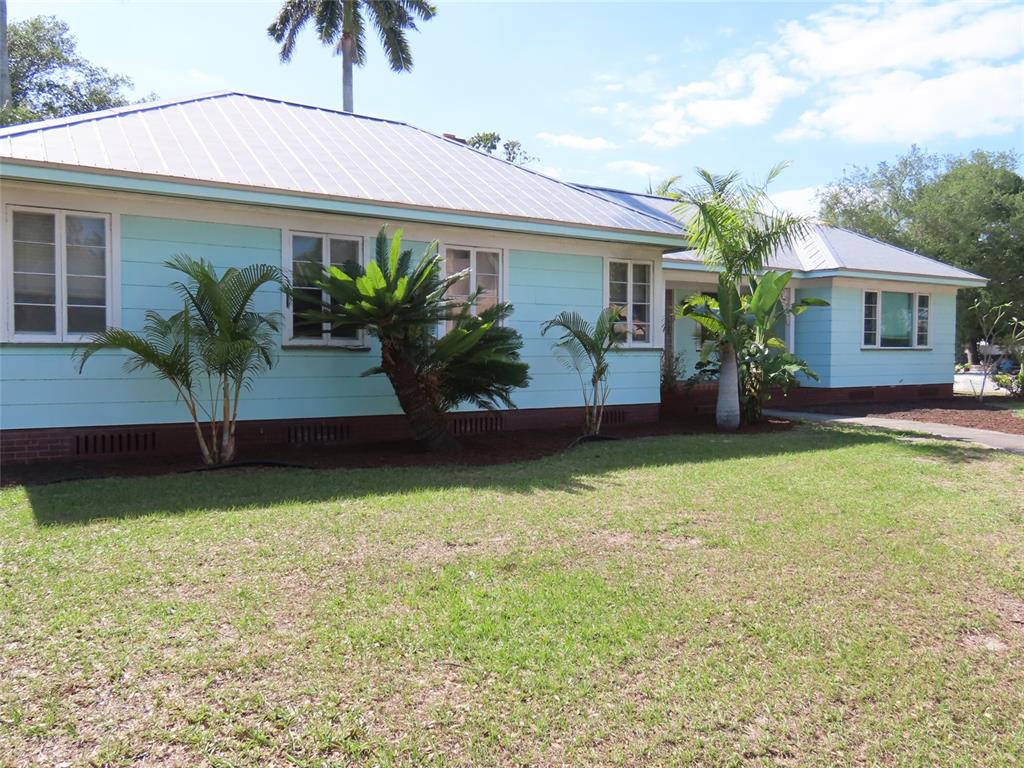 A light blue, single-story house with a metal roof and palm trees in the yard — 408 27TH STREET W, BRADENTON, FL
