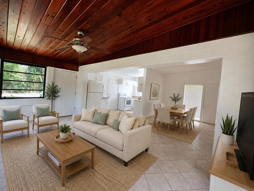 An open-concept living and dining area features a wood-paneled ceiling and tile flooring — 5825 YUCATAN DRIVE, ORLANDO, FL