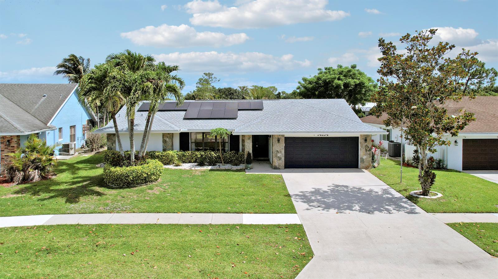 A single-story house with a gray roof, solar panels, and a two-car garage — 14154 Aster Avenue, Wellington FL 33414, WELLINGTON, FL