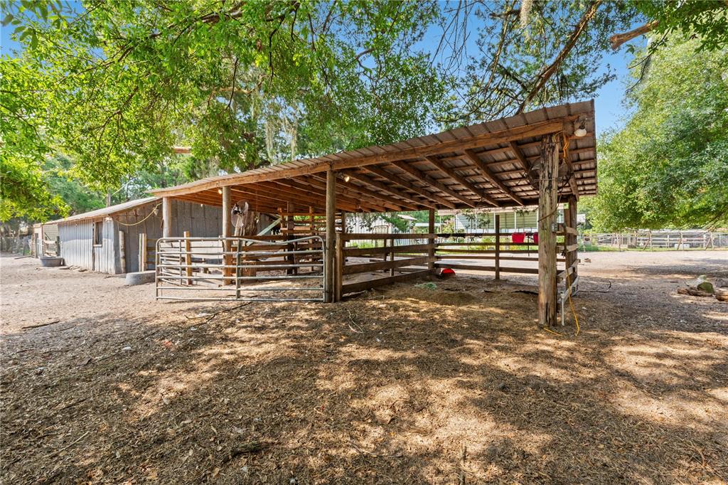 A wooden animal shelter with a metal roof stands in a dirt-covered outdoor area — 85276 HARTS ROAD, YULEE, FL