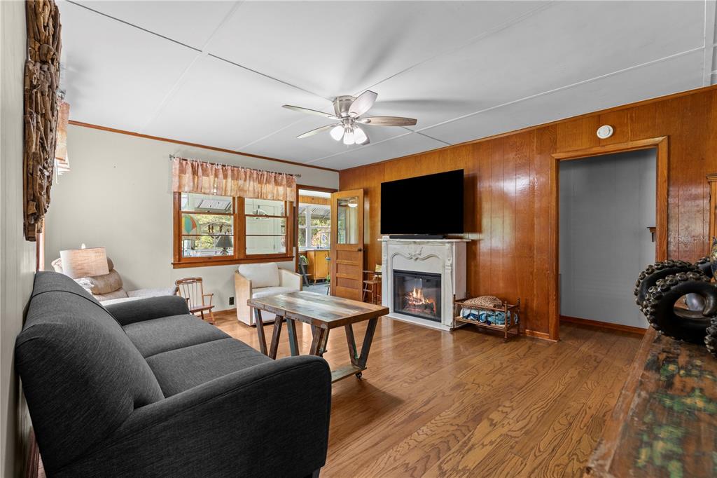 A living room features wood paneling, a fireplace with a television, and a dark sofa — 85276 HARTS ROAD, YULEE, FL