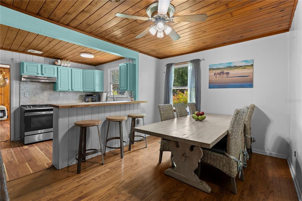A kitchen and dining area featuring wood-plank ceilings, turquoise cabinets, and a wooden breakfast bar — 85276 HARTS ROAD, YULEE, FL