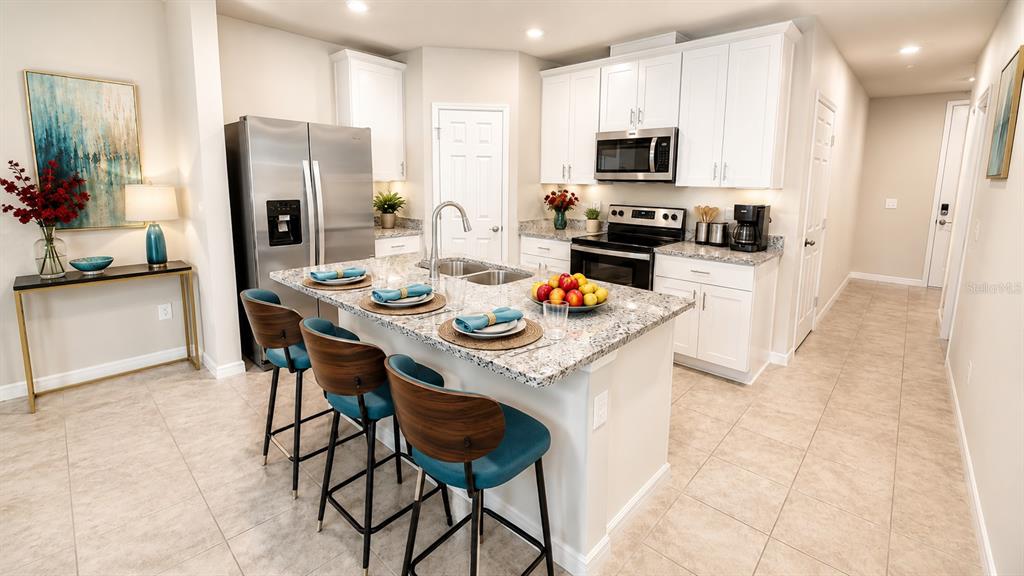 A modern kitchen features white cabinets, granite countertops, a center island, and stainless steel appliances — 1562 GRAND RUE DRIVE, CASSELBERRY, FL