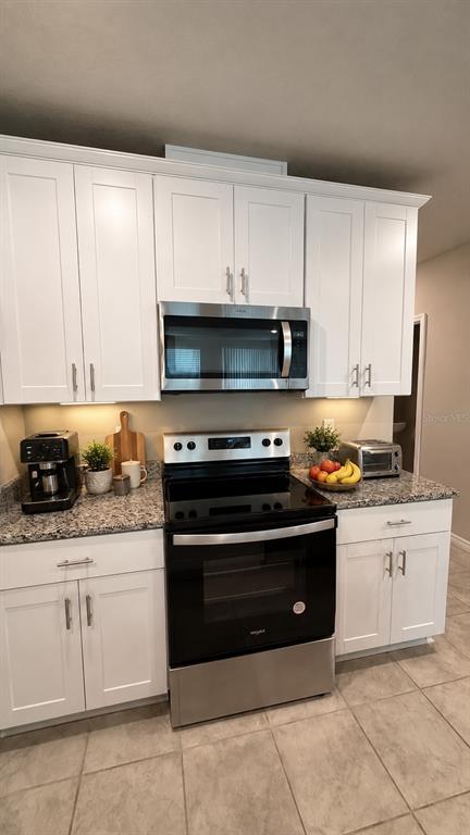 A kitchen features white cabinets, granite countertops, and stainless steel appliances — 1562 GRAND RUE DRIVE, CASSELBERRY, FL