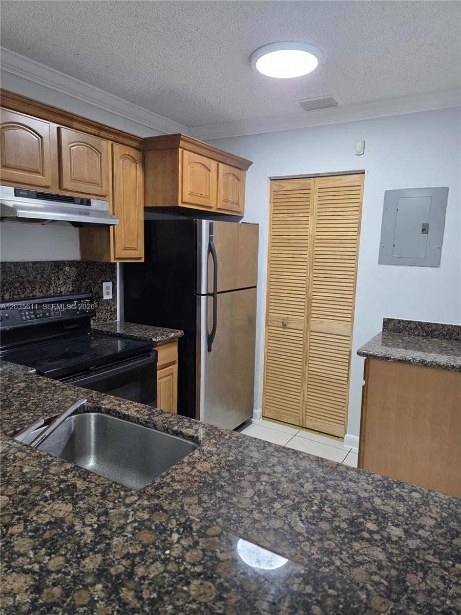 A kitchen features dark granite countertops, wooden cabinets, stainless steel appliances, and a louvered closet door — 1170 NW 80th Ave # 203, Margate FL 33063, MARGATE, FL