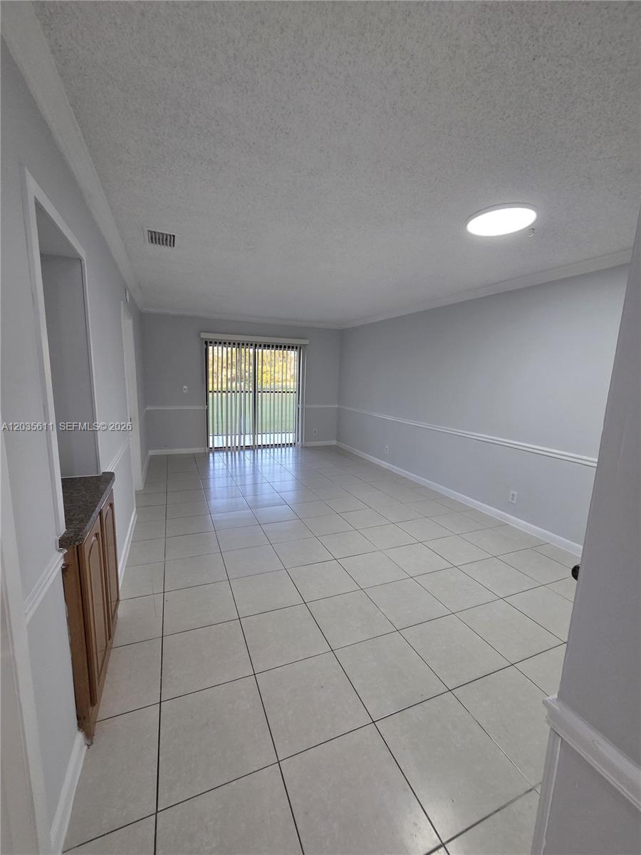 A living room with light gray walls, white tile flooring, and a sliding glass door — 1170 NW 80th Ave # 203, Margate FL 33063, MARGATE, FL