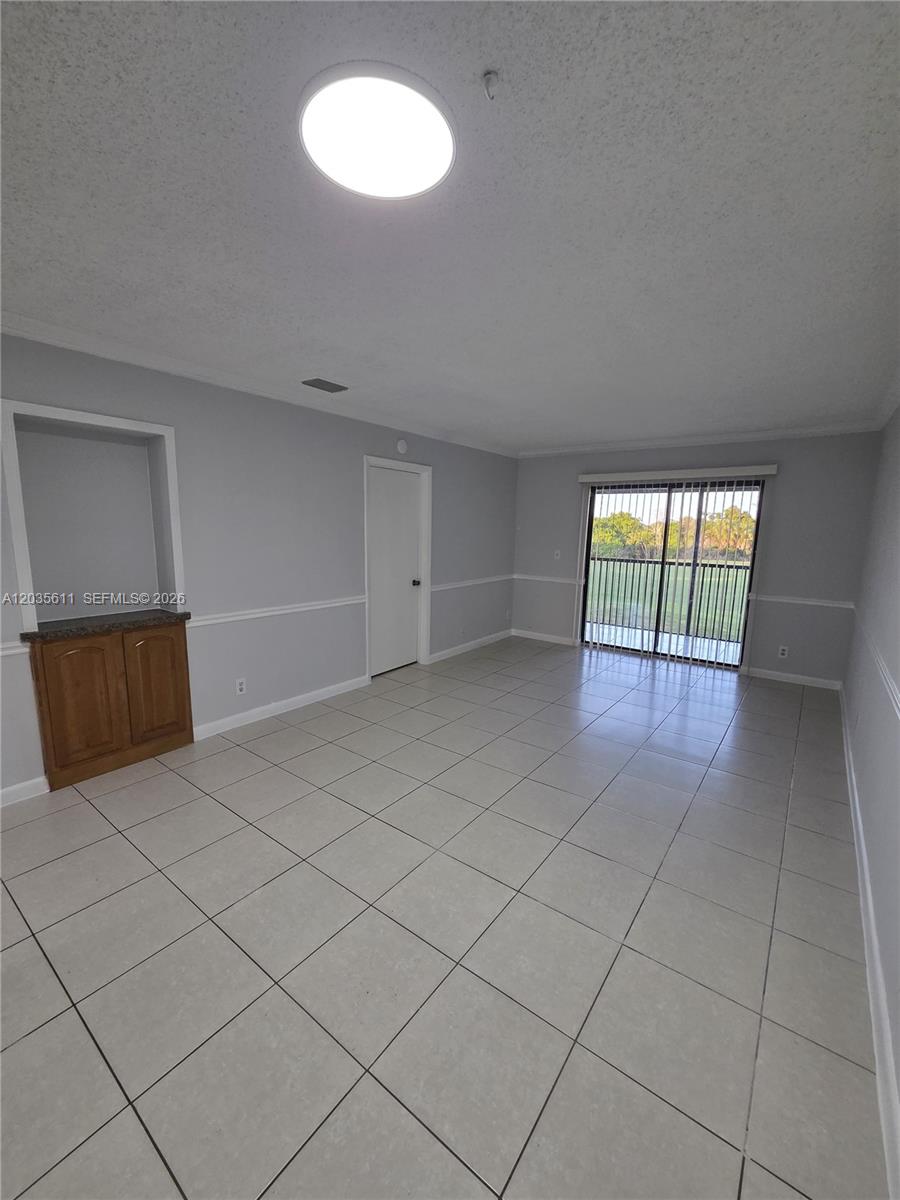 An empty room features light gray walls, white tile flooring, a built-in cabinet, and sliding doors — 1170 NW 80th Ave # 203, Margate FL 33063, MARGATE, FL