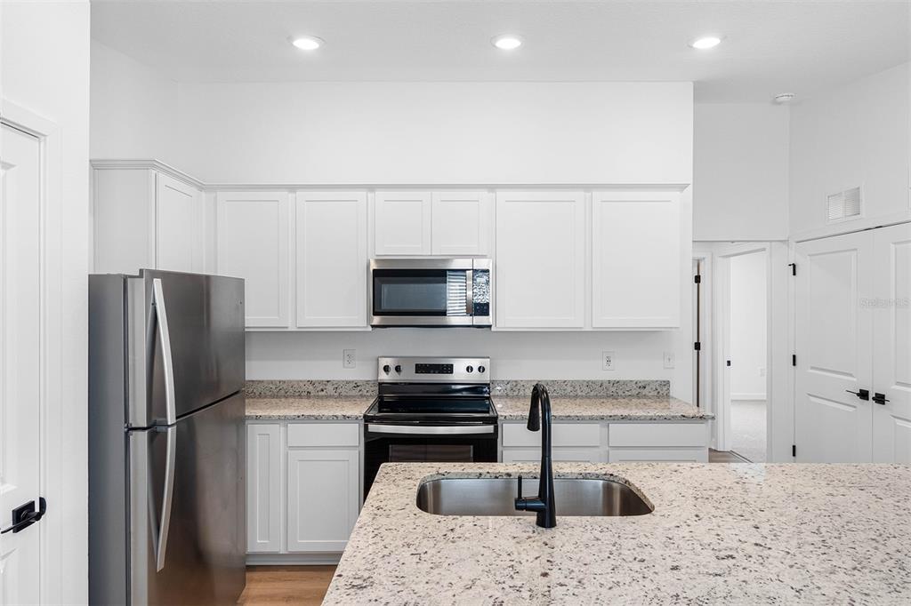 A kitchen features white cabinets, granite countertops, stainless steel appliances, and a central island — 15197 DUCK HAWK ROAD, BROOKSVILLE, FL