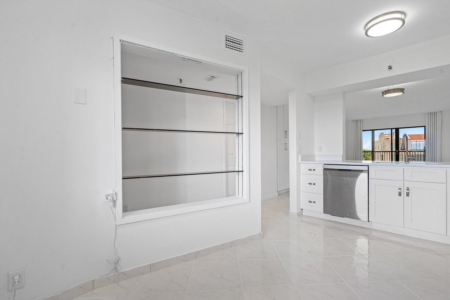 A white-walled room features a recessed wall niche with glass shelves and tile flooring — 14475 Strathmore Lane # 707, Delray Beach FL 33446, DELRAY BEACH, FL
