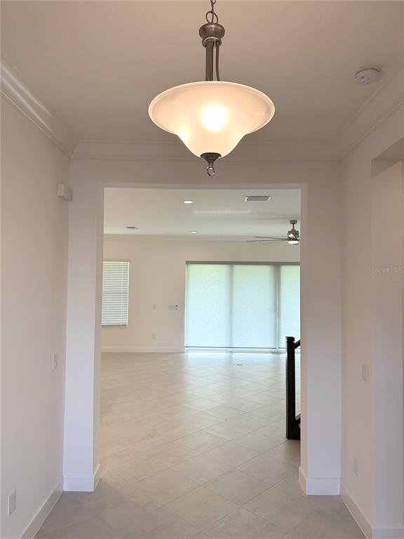A view through a doorway into a bright, tiled living area with large glass doors — 3392 ACACIA BAY AVENUE, WESLEY CHAPEL, FL