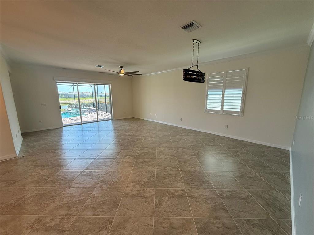 An open-concept living area features tile flooring, a ceiling fan, and sliding glass doors to a pool — 15153 SPANISH POINT DRIVE, PORT CHARLOTTE, FL