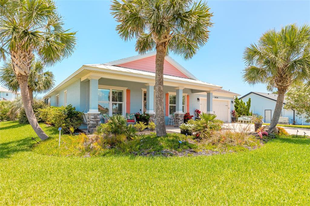 A light blue house with a pink gable, front porch, and palm trees in the yard — 2626 OSPREY CIRCLE N, FLAGLER BEACH, FL