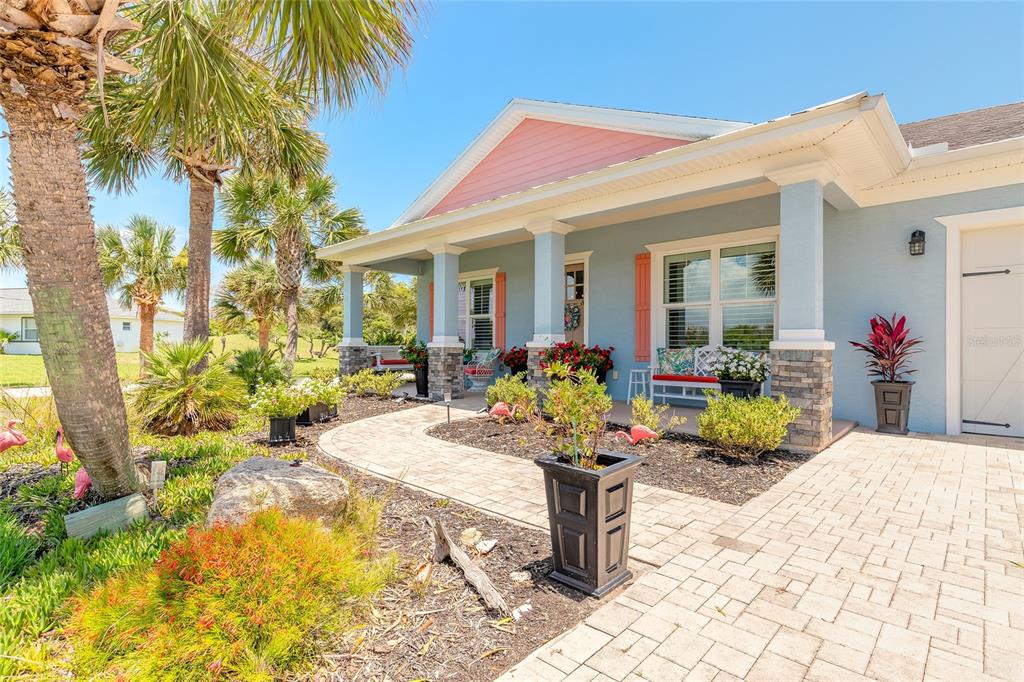 A light blue house with a covered porch, stone pillars, and a paver walkway — 2626 OSPREY CIRCLE N, FLAGLER BEACH, FL