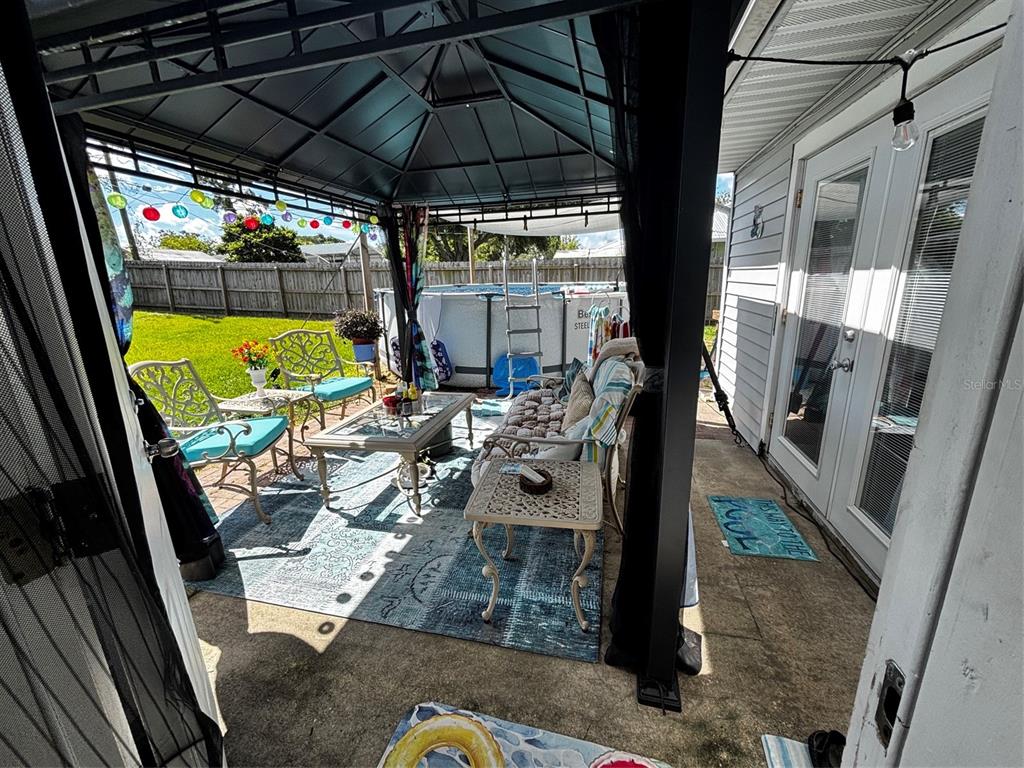 A covered patio features outdoor furniture, a rug, and a view of a backyard pool — 2737 FERN PALM DRIVE, EDGEWATER, FL