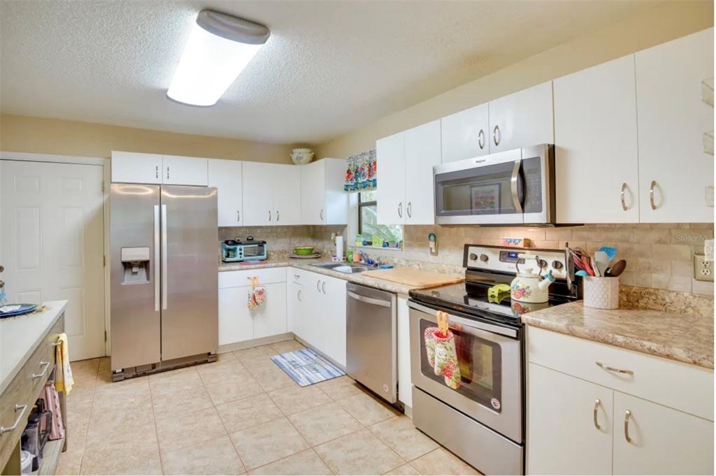 A kitchen with white cabinets, stainless steel appliances, and tan tile flooring — 2737 FERN PALM DRIVE, EDGEWATER, FL
