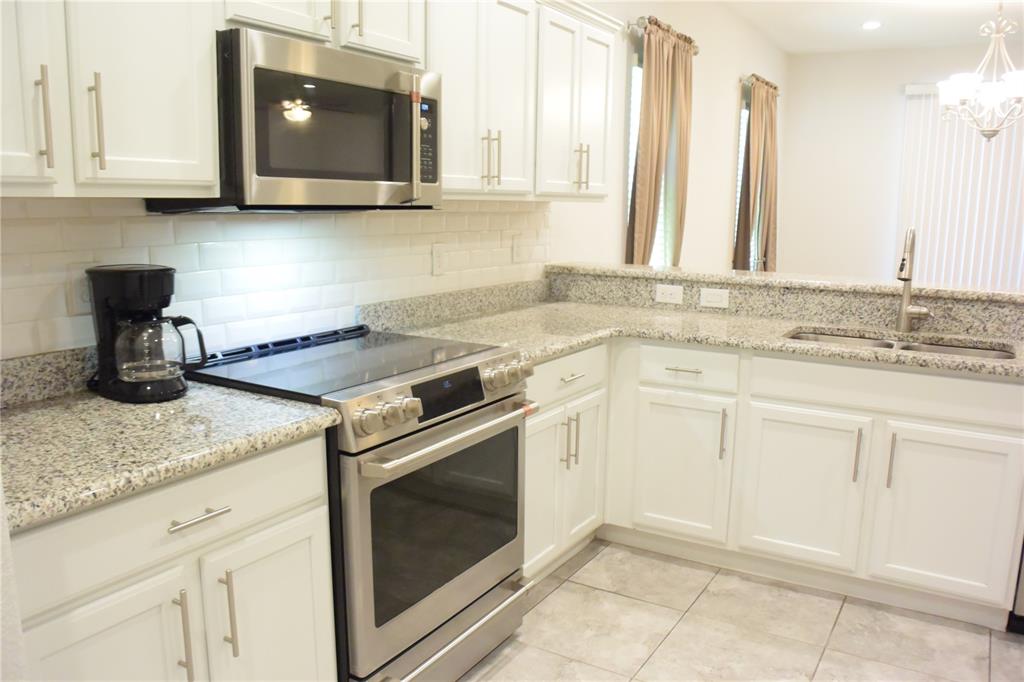 A kitchen with white cabinets, granite countertops, stainless steel appliances, and a subway tile backsplash — 1213 GRANTHAM DRIVE, SARASOTA, FL