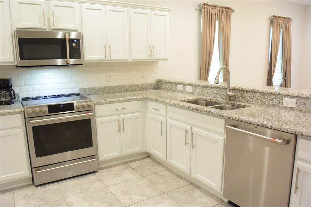 A kitchen with white cabinets, granite countertops, stainless steel appliances, and a subway tile backsplash — 1213 GRANTHAM DRIVE, SARASOTA, FL