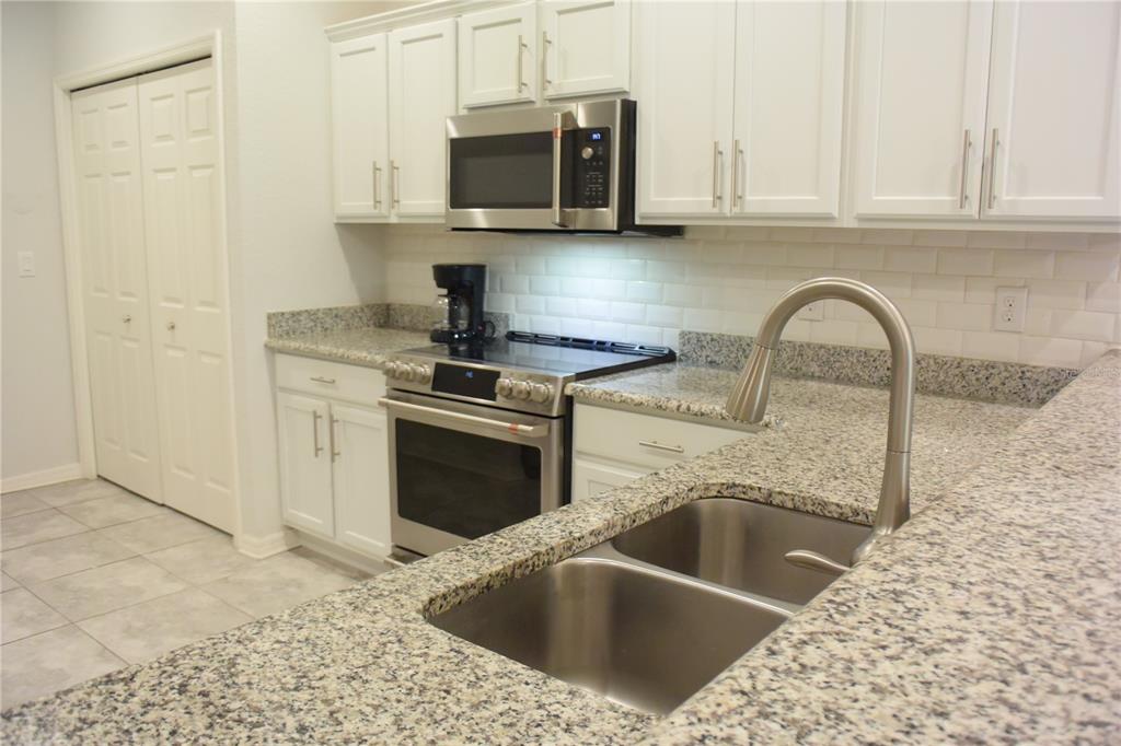 A kitchen features white cabinets, granite countertops, stainless steel appliances, and a double-basin sink — 1213 GRANTHAM DRIVE, SARASOTA, FL