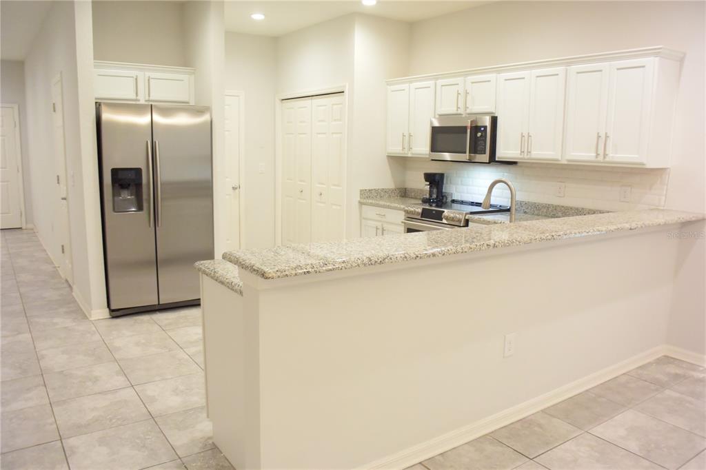 A kitchen with white cabinets, stainless steel appliances, and a granite-topped breakfast bar — 1213 GRANTHAM DRIVE, SARASOTA, FL