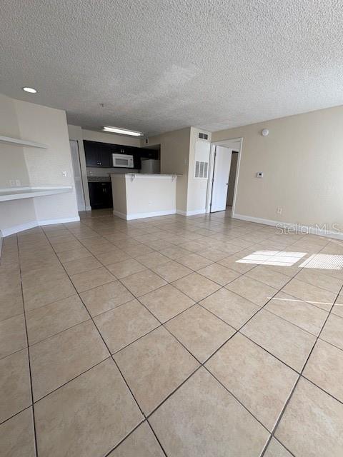 An open-concept living area features light-colored tile flooring and a kitchen with dark cabinetry — 2210 GRAND CAYMAN COURT UNIT 1722, KISSIMMEE, FL