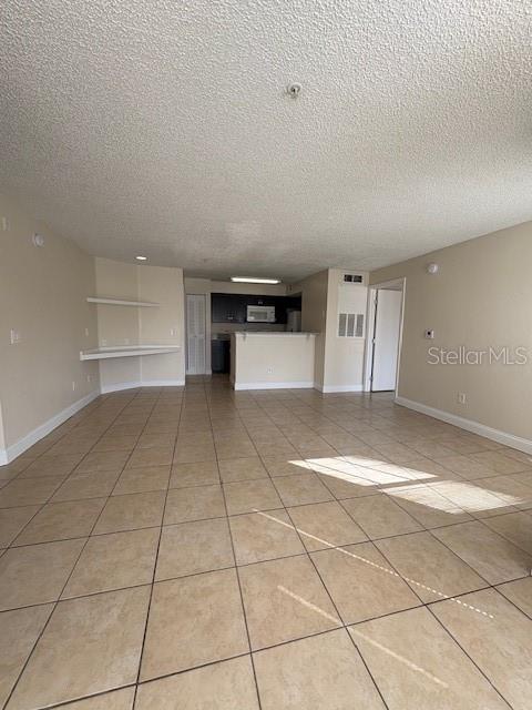 An open-concept living area features beige tile flooring, a kitchen with a breakfast bar, and shelving — 2210 GRAND CAYMAN COURT UNIT 1722, KISSIMMEE, FL