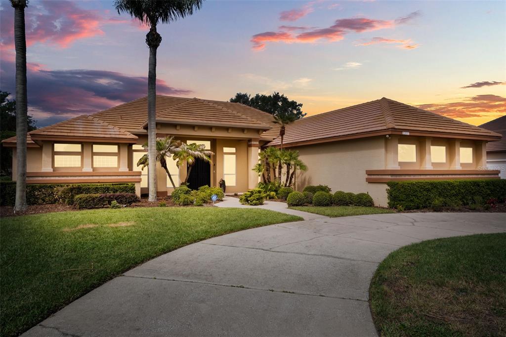 A single-story house with a tan stucco exterior, tile roof, and curved concrete driveway — 11217 WILLOW GARDENS DRIVE, WINDERMERE, FL