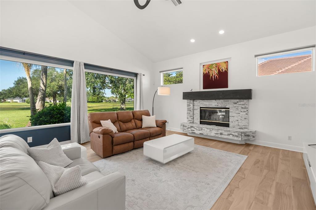 A living room features a stone fireplace, a brown leather sofa, and large windows — 11217 WILLOW GARDENS DRIVE, WINDERMERE, FL