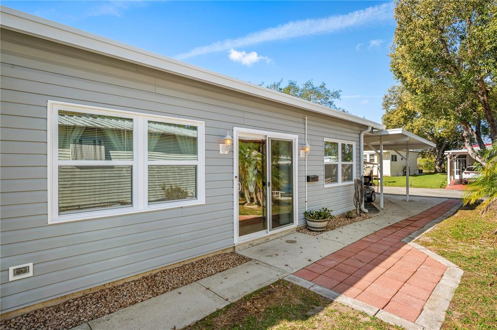The exterior of a gray-sided house features a sliding glass door and a brick walkway — 21 SILVERSIDES STREET, LAKE WALES, FL