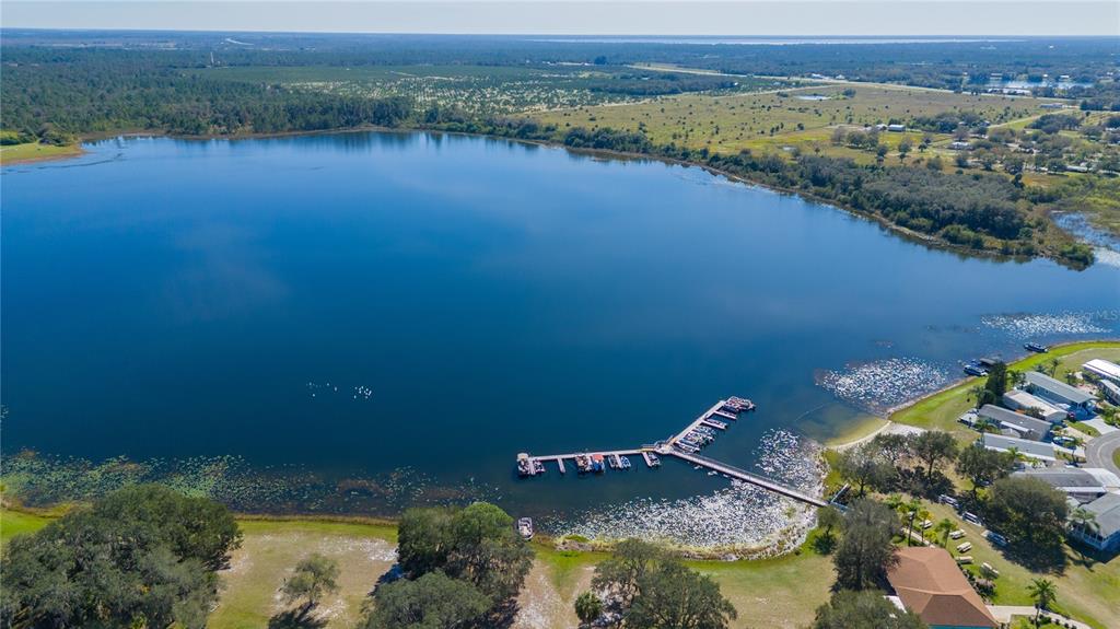 An aerial view shows a large lake with a long wooden dock and nearby houses — 21 SILVERSIDES STREET, LAKE WALES, FL