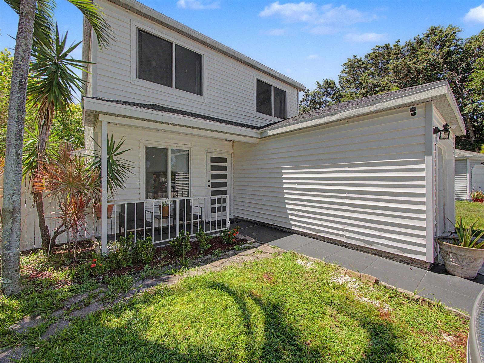A two-story white house with horizontal siding features a small front porch and walkway — 4675 Lakeside Circle, West Palm Beach FL 33417, WEST PALM BEACH, FL