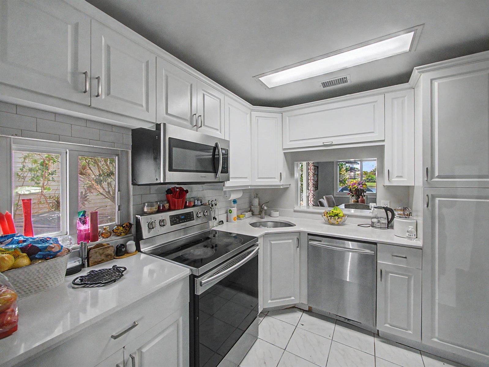 A kitchen features white cabinets, stainless steel appliances, a corner sink, and a window view — 4675 Lakeside Circle, West Palm Beach FL 33417, WEST PALM BEACH, FL