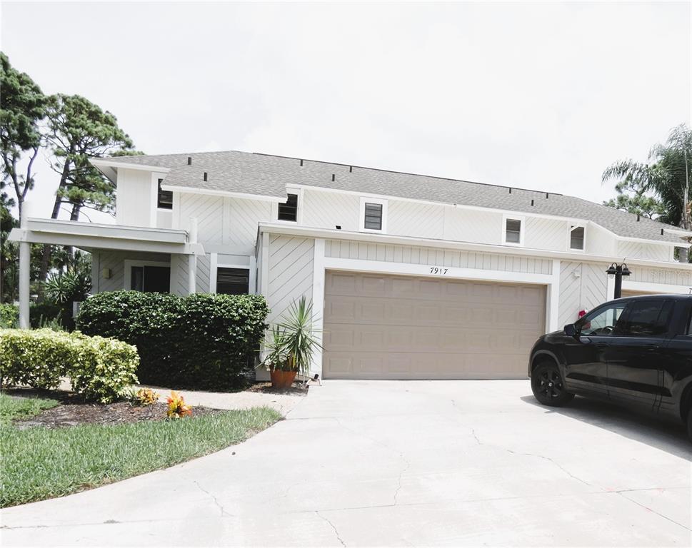 A two-story house with white vertical siding, a tan garage door, and a concrete driveway — 7917 PINEGROVE COURT UNIT 1, SARASOTA, FL