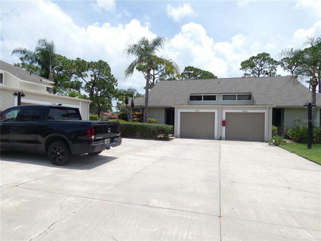 A black pickup truck is parked in the driveway of a single-story residential building — 7917 PINEGROVE COURT UNIT 1, SARASOTA, FL