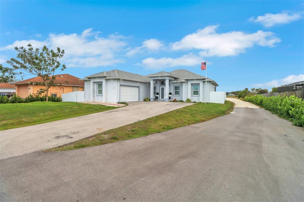 A single-story house with a gray roof, white exterior, and a paved driveway — 2394 45TH AVENUE NE, NAPLES, FL