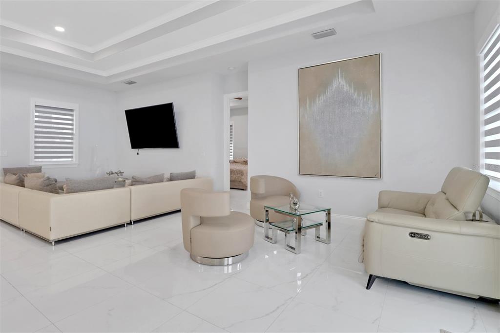 A bright living room features white tile floors, a large sectional sofa, and modern seating — 2394 45TH AVENUE NE, NAPLES, FL