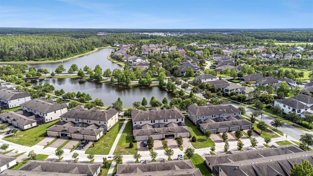 An aerial view shows multiple multi-family residential buildings situated near a large community pond — 13027 BATTEN LANE, ODESSA, FL