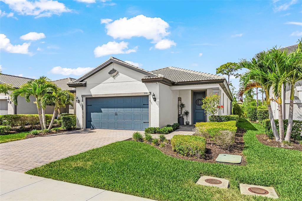 A single-story house with a blue garage door, a tiled roof, and a front lawn — 3990 SPOTTED EAGLE WAY, FORT MYERS, FL