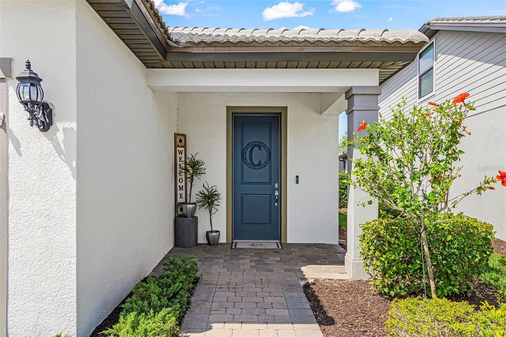 A blue front door with a letter C monogram sits under a covered entryway — 3990 SPOTTED EAGLE WAY, FORT MYERS, FL